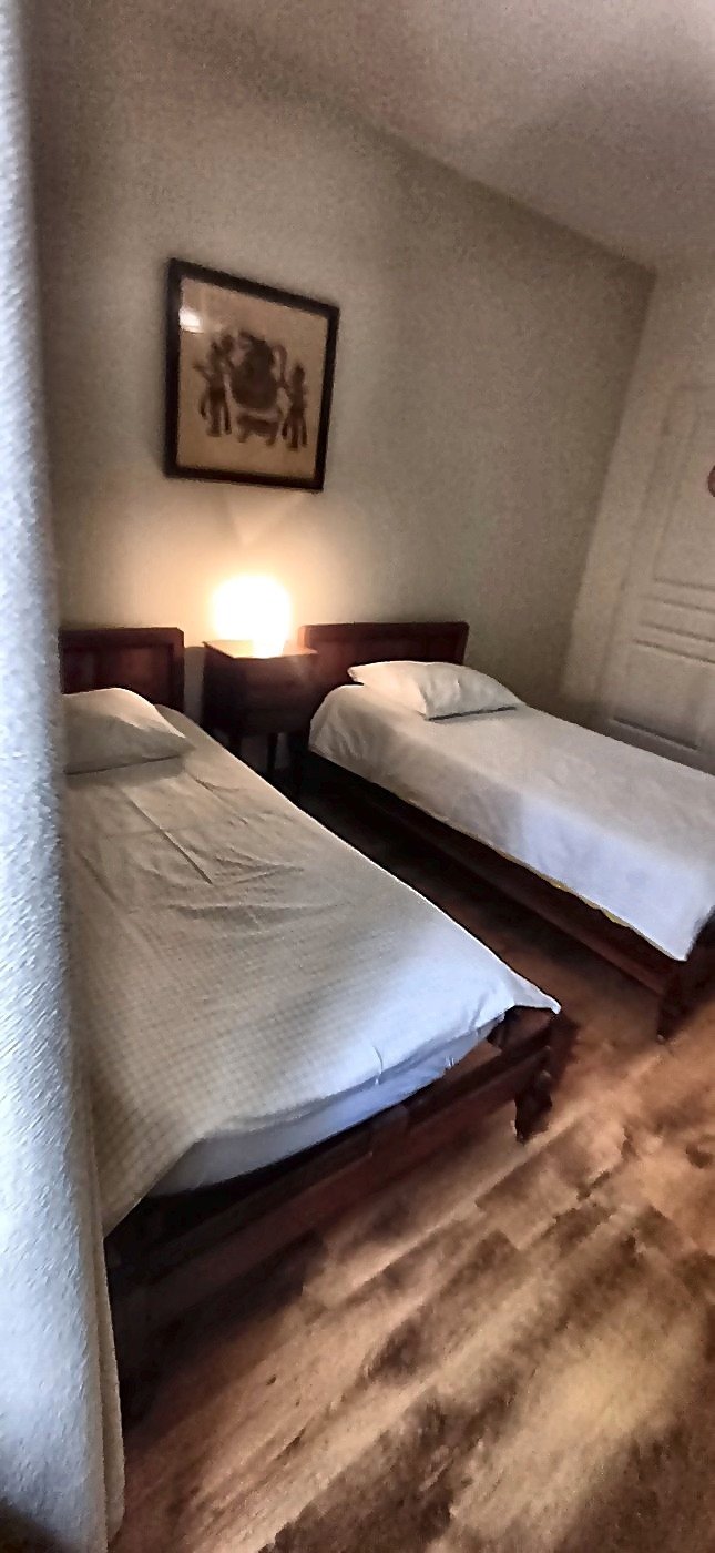 Deux lits simples confortables avec tables de chevet et éclairage chaleureux